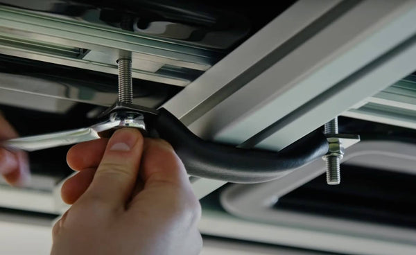 Person tightening nuts on TentBox universal mounting mechanism during installation