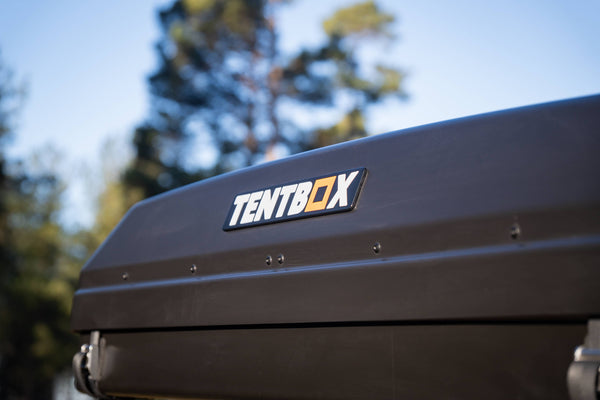 Close up of a closed TentBox Classic 2.0 with trees and a blue sky in the background